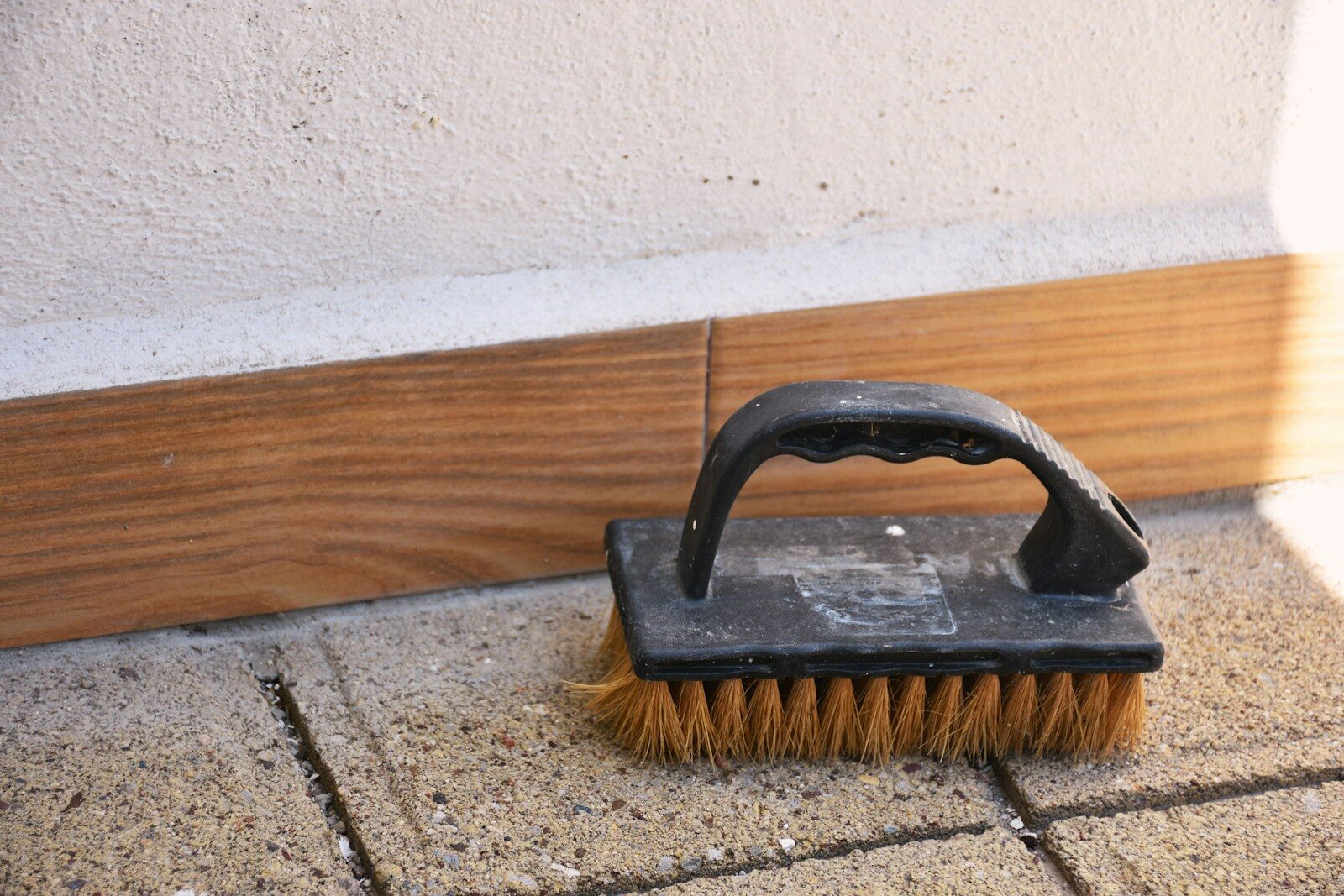 A scrubbing brush rests on a stone patio.