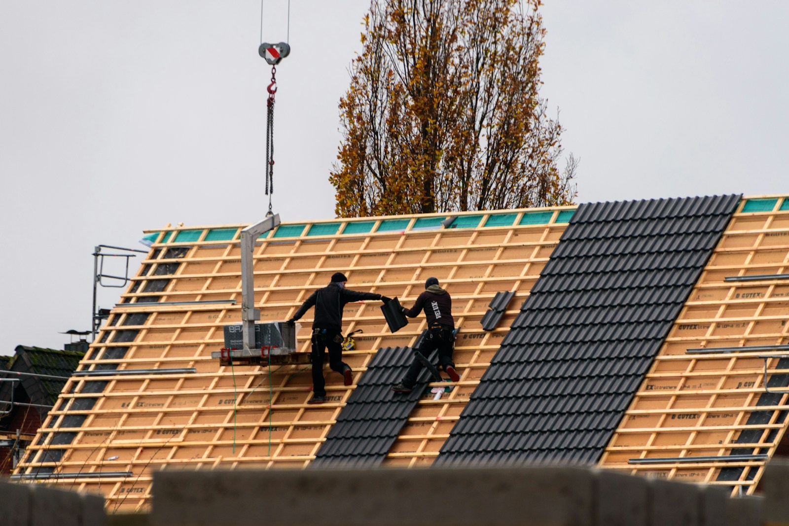 Construction workers installing roof tiles on a new building.